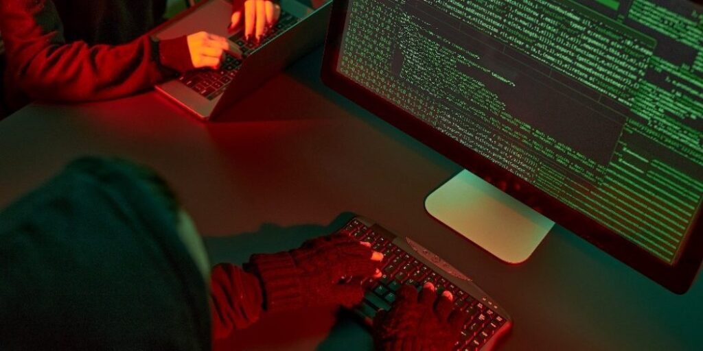 Hacker usando computador com códigos na tela, representando ataques cibernéticos mais comuns em 2024